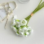 White silk lotus flower bouquet with decorative ribbon on a clean background.