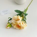 Silk artificial peony bouquet with creamy yellow blooms and green leaves for floral decor