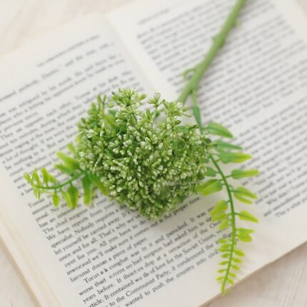 Realistic artificial flower arrangement placed on an open book next to foliage.