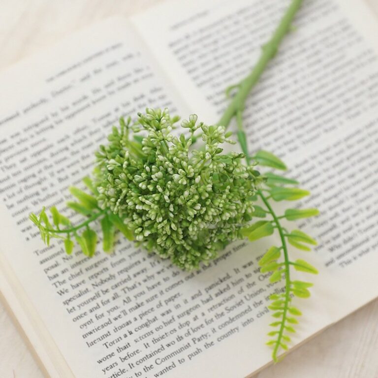 Realistic artificial flower arrangement placed on an open book next to foliage.
