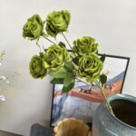 Six heads of realistic artificial silk roses arranged for home decoration.
