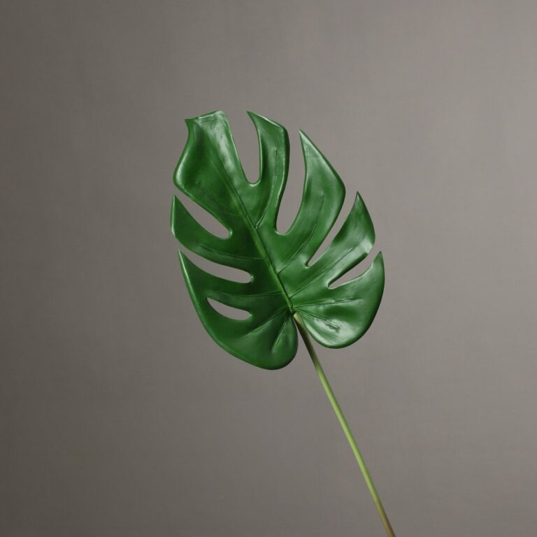 Lush green artificial flower Monstera leaf made from silk material.