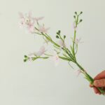 Delicate artificial silk daisy bouquet with white and light pink blossoms on green stems.