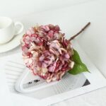 Realistic silk pink hydrangea bouquet displayed on architectural blueprints and modern surface.