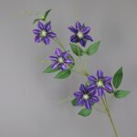 Artificial flower display featuring silk clematis blooms on green stems.