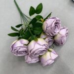 Cluster of lilac silk rose heads with green foliage; realistic artificial floral bouquet.