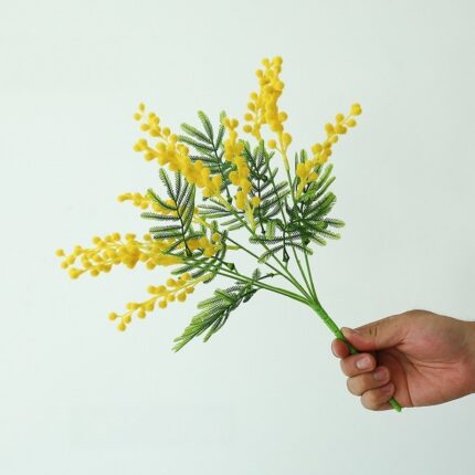 Artificial yellow acacia flower cluster bouquet with green foliage.