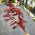 Deep red artificial tea tree branches used for vibrant faux floral arrangements.