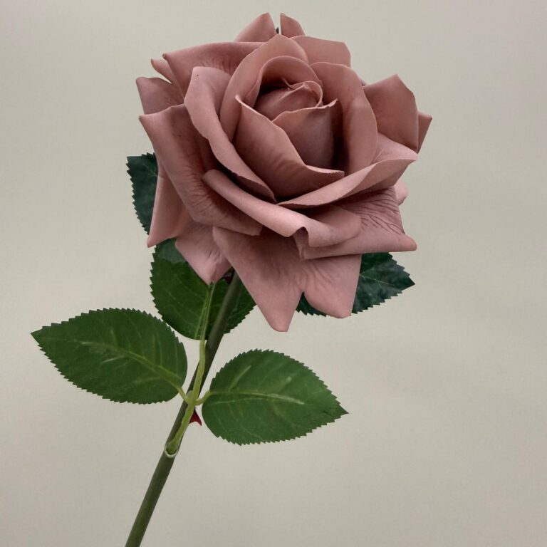 Realistic artificial pink rose bloom with deep green leaves.
