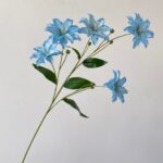 Branch of faux blue lilies, a realistic artificial flower perfect for wedding decorations.