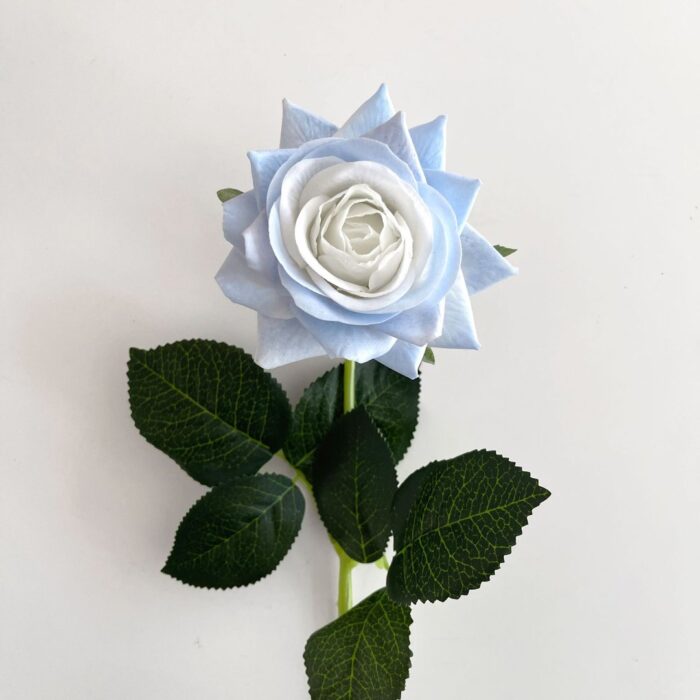 Close-up of faux wedding flowers: a delicate light blue artificial flower arrangement with green leaves.