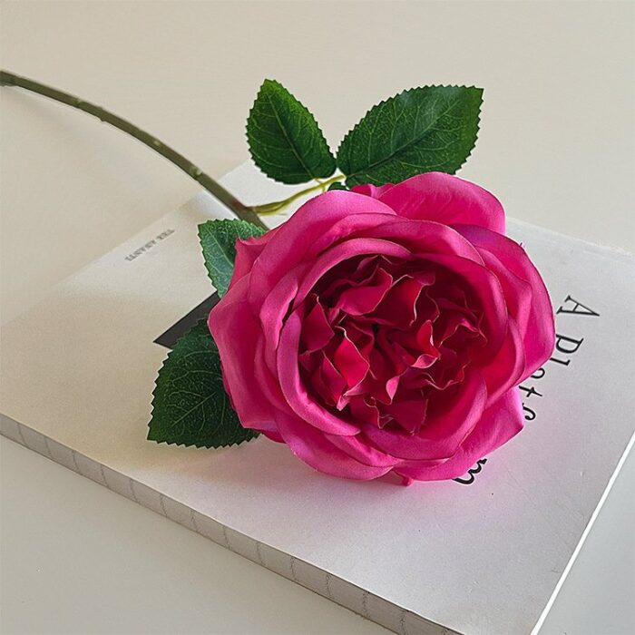 A vibrant pink faux rose, an artificial flower perfect for wedding decor and bouquets.