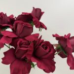 Close-up photo of multiple deep red faux roses showing delicate petal textures and layered details.