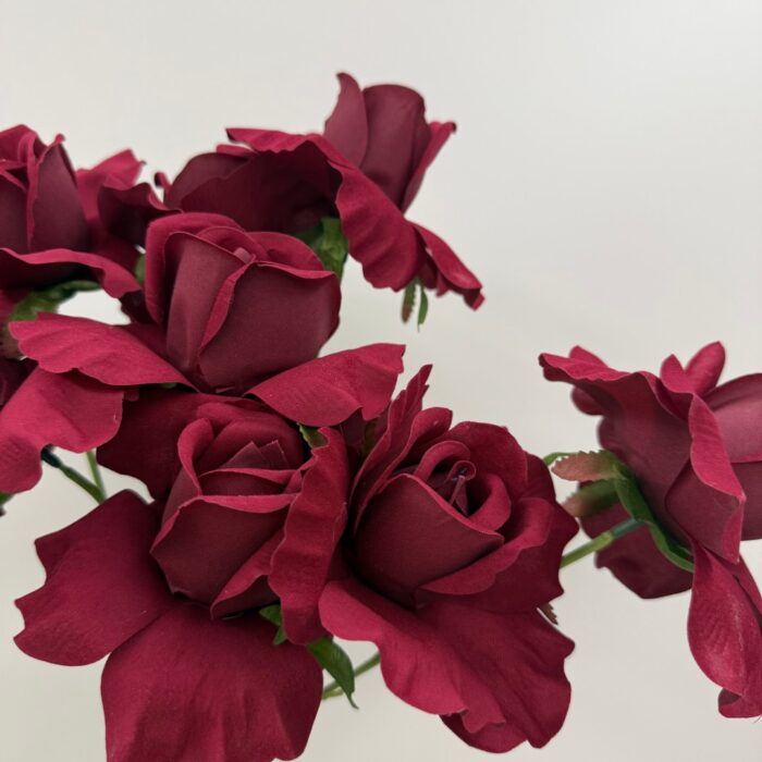 Close-up photo of multiple deep red faux roses showing delicate petal textures and layered details.