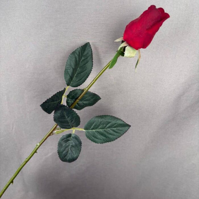 Classic Red Artificial Rose Bud Stem with Leaves Single red artificial rose bud stem with detailed green leaves and realistic thorny stem on a gray background.